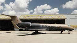 A black and tan airplane parked in front of an aircraft hangar with a sign on it that reads: VIP Completions A black and tan airplane parked in front of an aircraft hangar with a sign on it that reads: VIP Completions