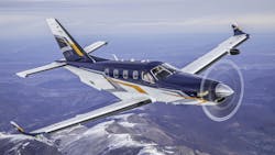 A white airplane with gold and dark blue accents flying over mountains A white airplane with gold and dark blue accents flying over mountains