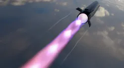 A black missile flying through a dark sky with a purple trail of light behind it