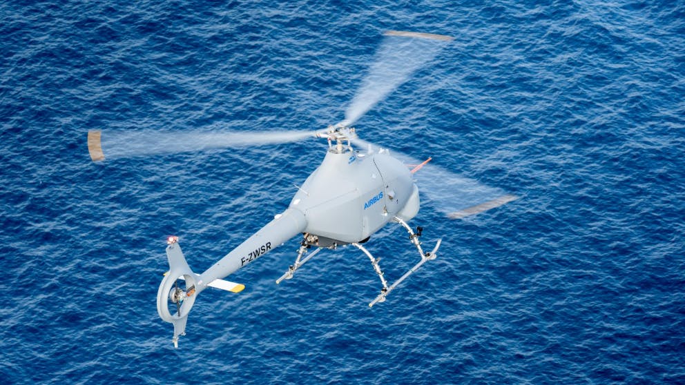 A white helicopter flying over blue water
