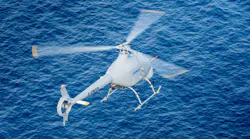 A white helicopter flying over blue water