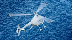 A white helicopter flying over blue water A white helicopter flying over blue water