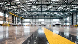 A wide shot of an aircraft maintenance hangar with a shiny brown, black, and yellow floor and four airplanes sitting inside A wide shot of an aircraft maintenance hangar with a shiny brown, black, and yellow floor and four airplanes sitting inside