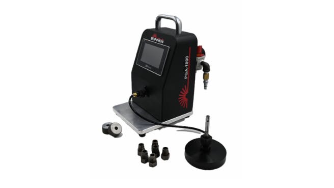 A black air gage with a screen, a metal handle and several attachments sitting in front of it