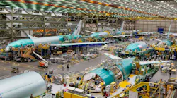 A hangar showing airplanes and machinery with people working around the machines