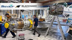 The interior of a maintenance hangar showing two technicians walking near an airplane that has been taken apart and an engine on a stand. There's text in the corner showing two logos that read: 'Seair Seaplanes' and 'Blackhawk by The Blackhawk Group' The interior of a maintenance hangar showing two technicians walking near an airplane that has been taken apart and an engine on a stand. There's text in the corner showing two logos that read: 'Seair Seaplanes' and 'Blackhawk by The Blackhawk Group'
