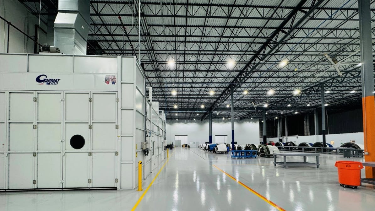 The interior of a maintenance hangar with large storage containers to the left and worktables and equipment to the right