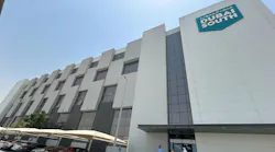 The exterior of a building with white brick and dark glass with a sign on the front that reads: DUBAI SOUTH