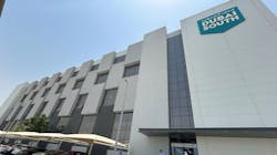 The exterior of a building with white brick and dark glass with a sign on the front that reads: DUBAI SOUTH The exterior of a building with white brick and dark glass with a sign on the front that reads: DUBAI SOUTH