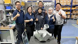 A group of maintenance technicians smiling at the camera with some giving a thumbs-up hand gesture, all standing behind an aircraft component in a repair shop A group of maintenance technicians smiling at the camera with some giving a thumbs-up hand gesture, all standing behind an aircraft component in a repair shop