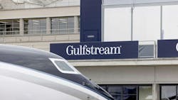The front part of an airplane in front of a building with a sign on it that says, 'GULFSTREAM' The front part of an airplane in front of a building with a sign on it that says, 'GULFSTREAM'