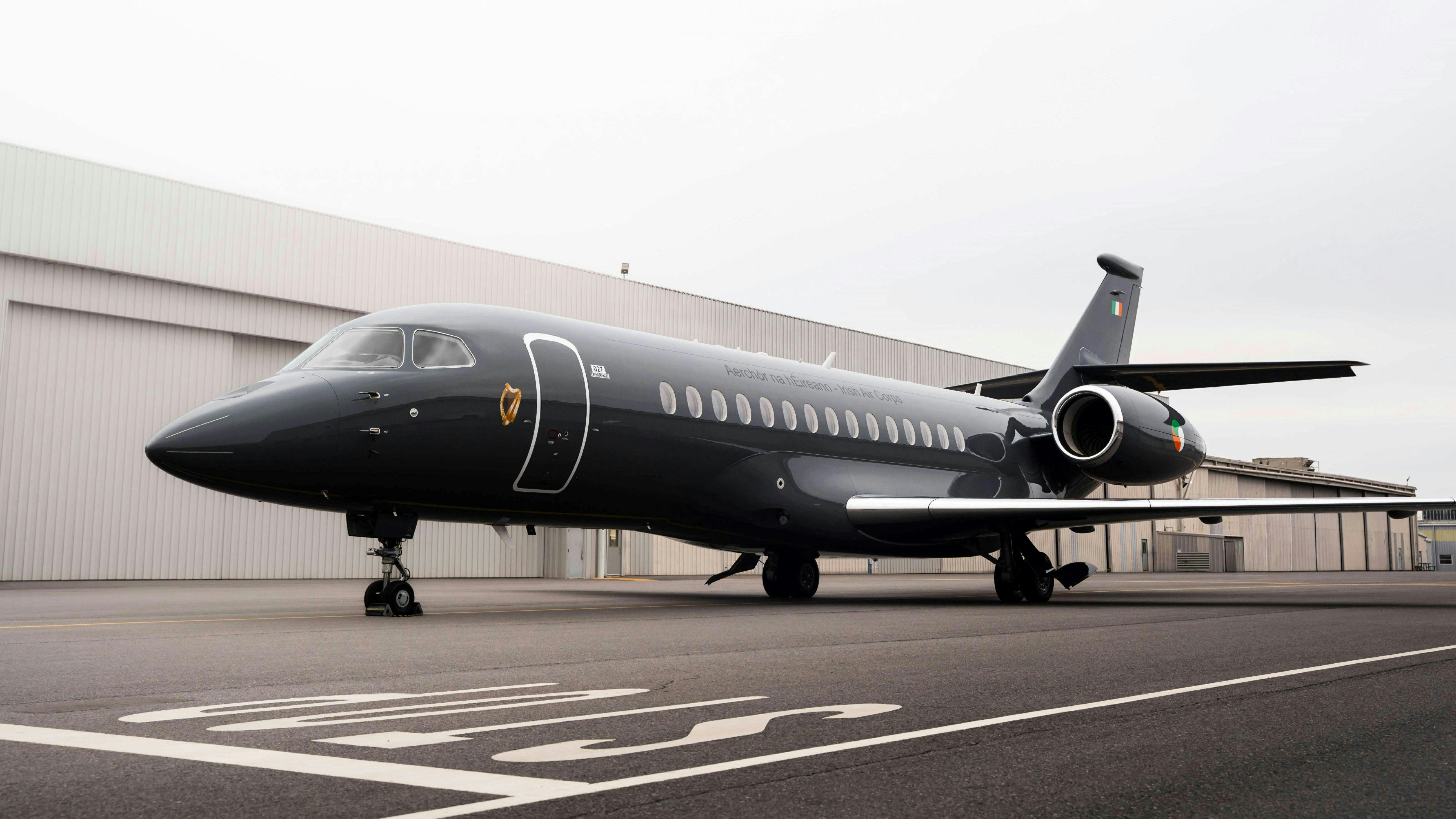 A large black airplane on a tarmac in front of beige buildings