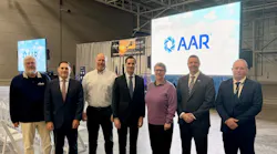 A group of professionals in business attire standing in a conference room in front of backdrops that read: AAR
