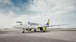 A white airplane with blue and yellow accents and text on the side that reads: flyadeal