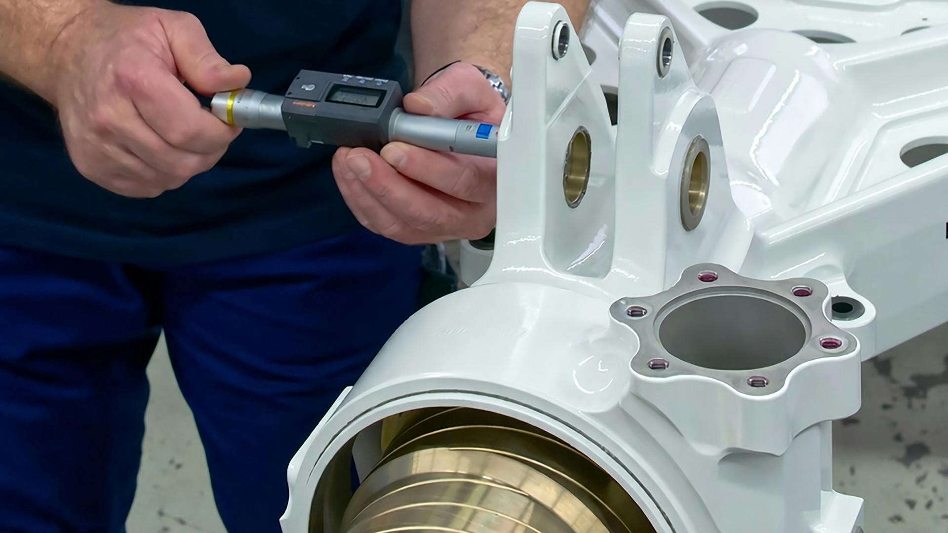 A close-up shot of a technician's hands using a hand tool on a piece of landing gear