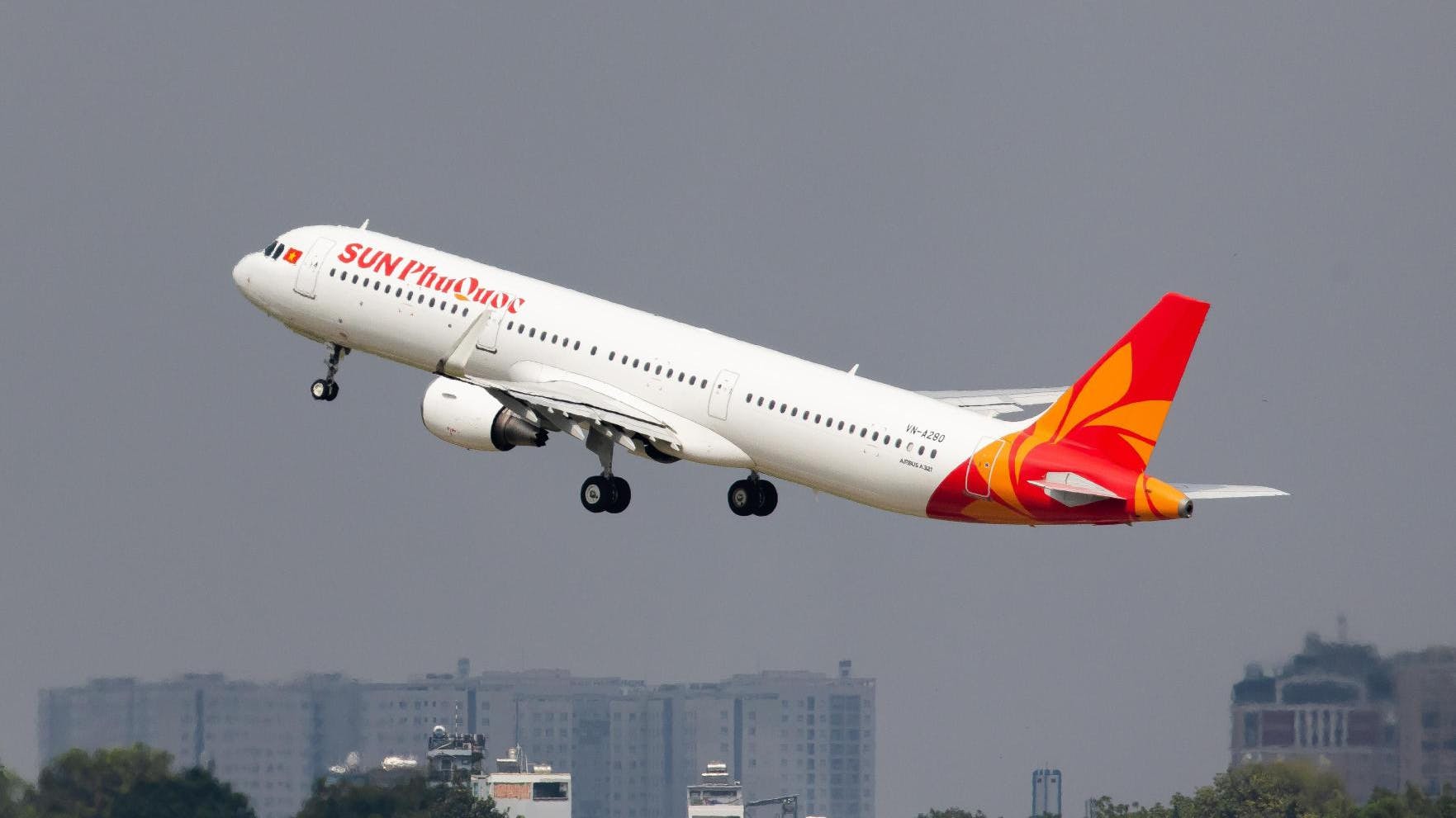 A white airplane with a red and orange tail with text on the side that reads: Sun PhuQuoc Airways