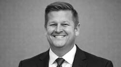 A black-and-white photo of a man wearing a suit and tie smiling at the camera A black-and-white photo of a man wearing a suit and tie smiling at the camera