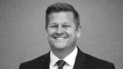 A black-and-white photo of a man wearing a suit and tie smiling at the camera A black-and-white photo of a man wearing a suit and tie smiling at the camera