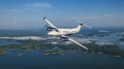 A white airplane with blue accents flying over a body of water with islands in it A white airplane with blue accents flying over a body of water with islands in it