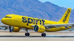 A yellow airplane with the word 'Spirit' printed on it parked on a tarmac in front of mountains A yellow airplane with the word 'Spirit' printed on it parked on a tarmac in front of mountains