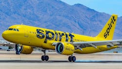 A yellow airplane with the word 'Spirit' printed on it parked on a tarmac in front of mountains A yellow airplane with the word 'Spirit' printed on it parked on a tarmac in front of mountains
