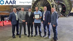 A group of men in business attire standing in front of an airplane engine with a banner above the image that reads: AAR Doing It Right A group of men in business attire standing in front of an airplane engine with a banner above the image that reads: AAR Doing It Right