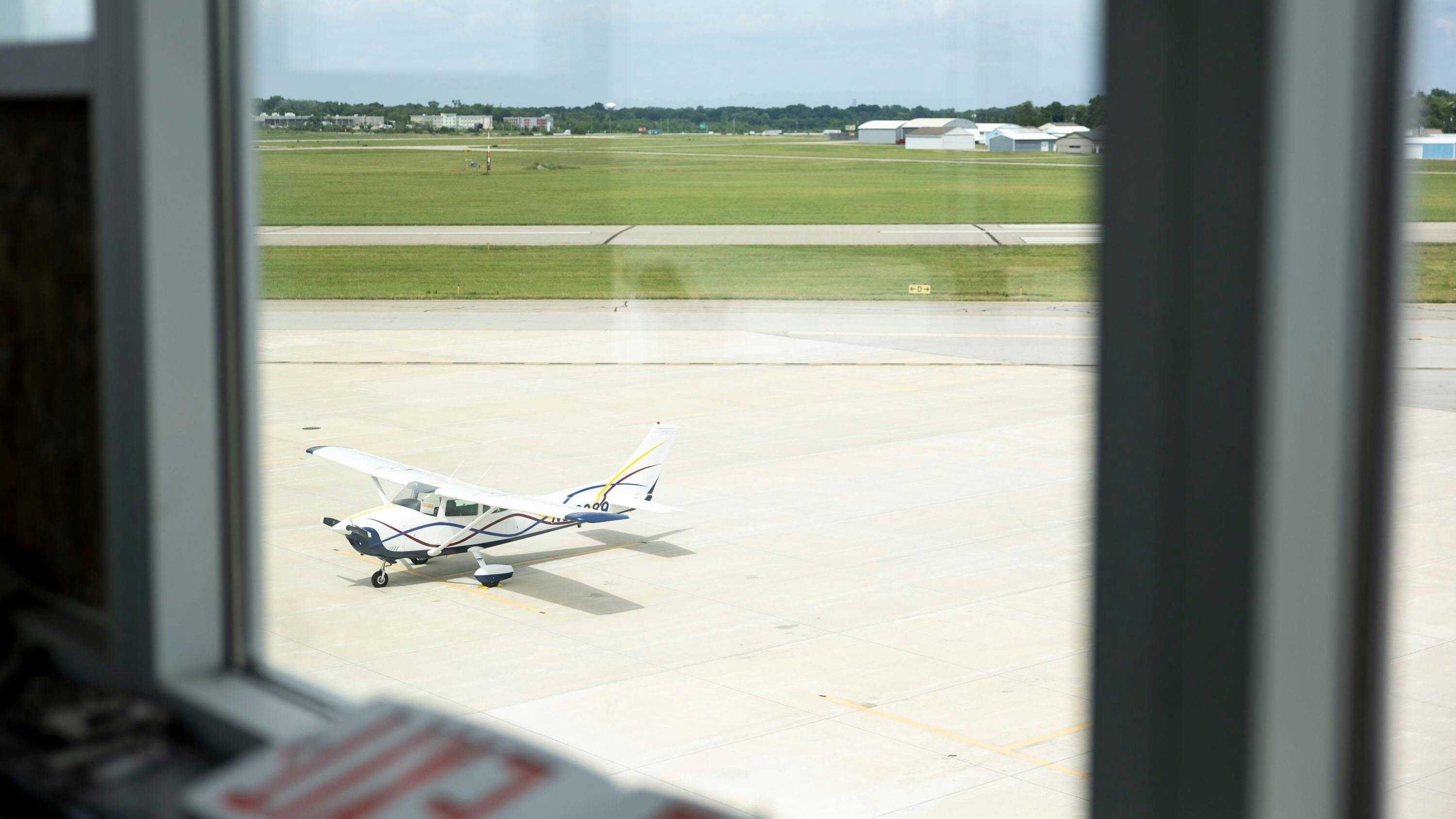 A view through a window of a white airplane parked on a tarmac