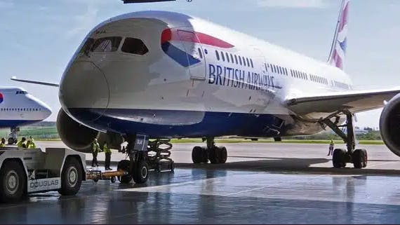 A white airplane with a blue bottom and red and blue accents that says, 'British Airways' on the side