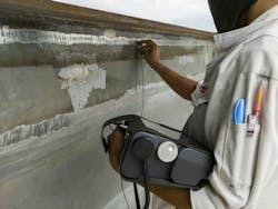 A technician holding a non-destructive testing device while pressing the handheld part of the system to an airplane A technician holding a non-destructive testing device while pressing the handheld part of the system to an airplane