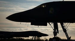 A silhouette of two aircraft standing near trees against a pale blue sky with clouds A silhouette of two aircraft standing near trees against a pale blue sky with clouds