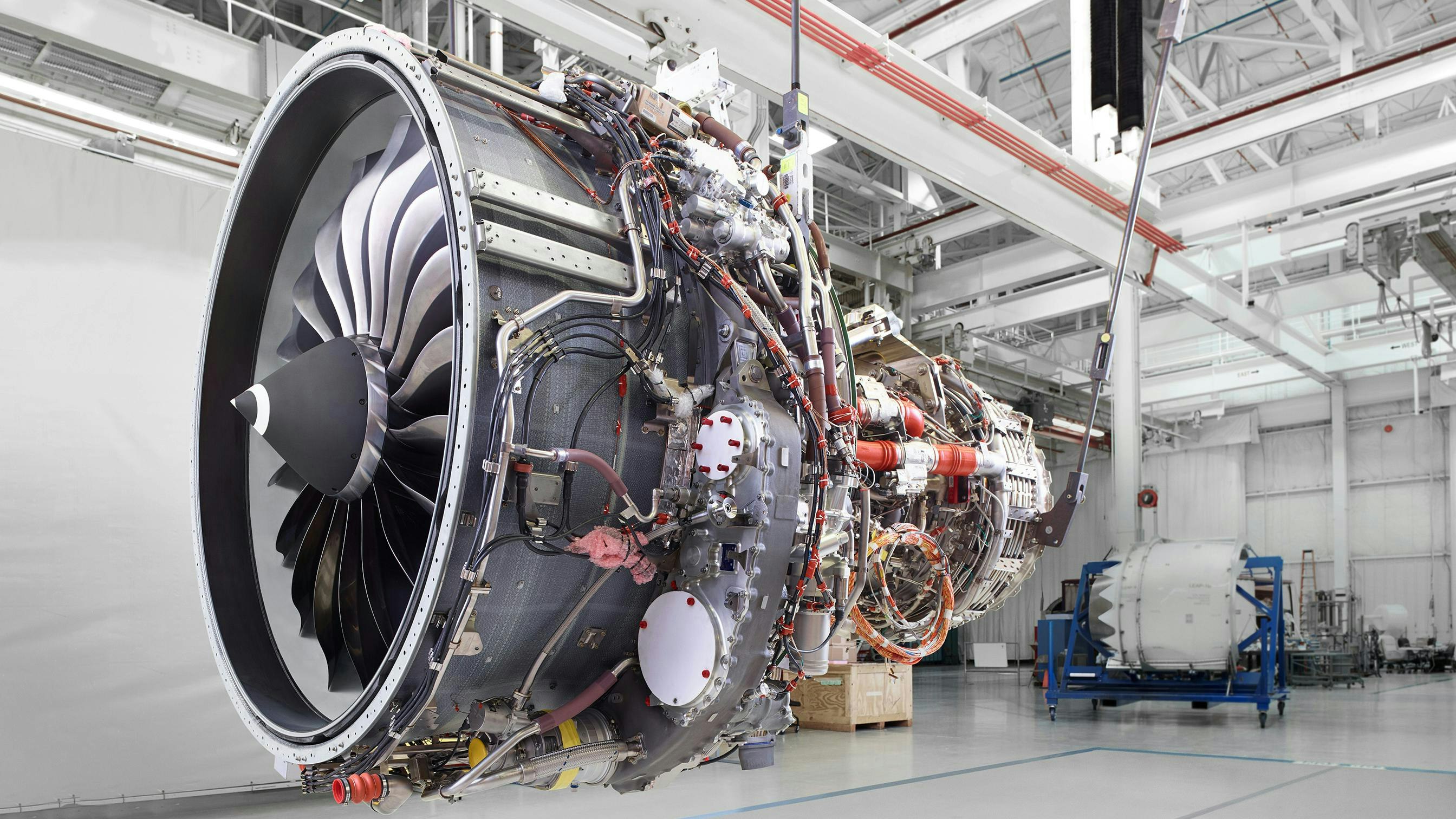 An airplane engine hanging from the ceiling in a repair shop, not attached to a plane