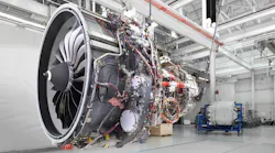 An airplane engine hanging from the ceiling in a repair shop, not attached to a plane