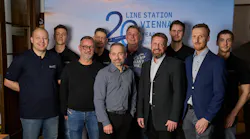 A group of professionals in varying styles of dress standing in front of a backdrop that reads: LINE STATION VIENNA 20 YEARS