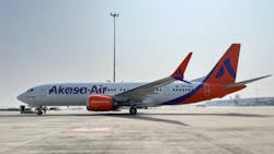 A white airplane with red accents on the tail and wings and text printed on the side that reads: Akasa Air A white airplane with red accents on the tail and wings and text printed on the side that reads: Akasa Air