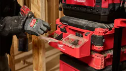 A gloved hand holding a nail next to a toolbox with a compartment on the side filled with nails and screws A gloved hand holding a nail next to a toolbox with a compartment on the side filled with nails and screws