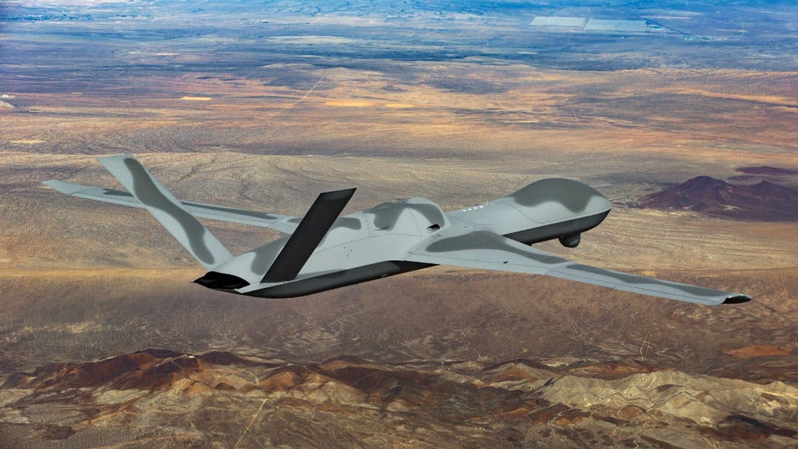 An aircraft with a camouflage-like pattern painted on it flying over a desert