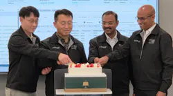 Four men cutting a celebratory cake while standing in front of a projection of an Excel sheet Four men cutting a celebratory cake while standing in front of a projection of an Excel sheet