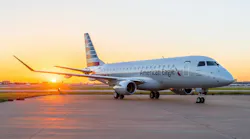 A large airplane with 'American Eagle' printed on the side parked on a tarmac with a sunset behind it