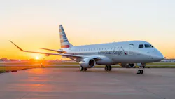 A large airplane with 'American Eagle' printed on the side parked on a tarmac with a sunset behind it A large airplane with 'American Eagle' printed on the side parked on a tarmac with a sunset behind it