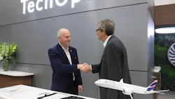 Two men wearing suits shaking hands while standing behind a desk displaying a model airplane Two men wearing suits shaking hands while standing behind a desk displaying a model airplane