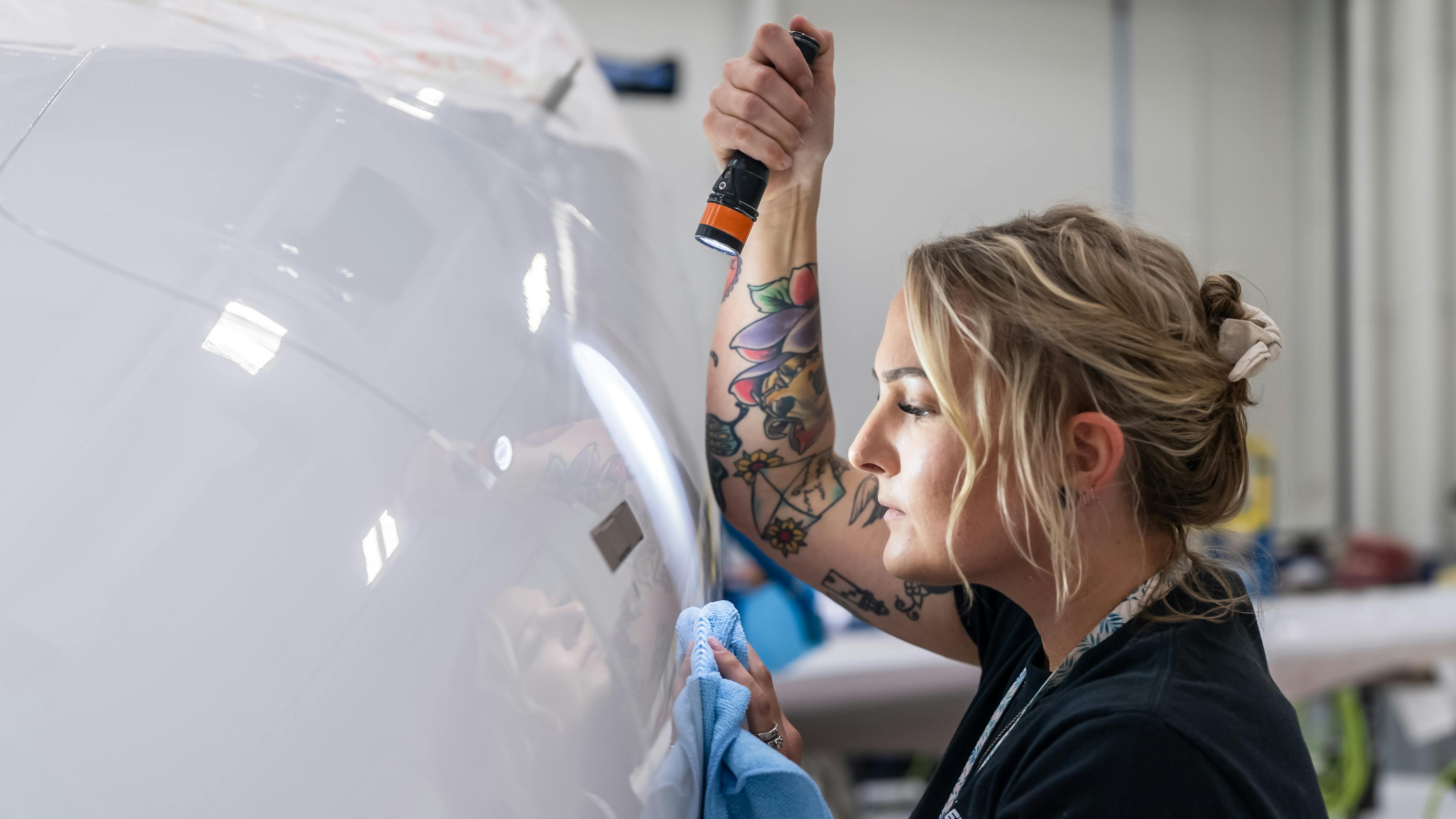 A woman holding a flashlight and inspecting an airplane up close