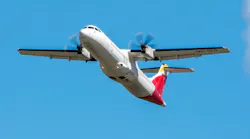 A white airplane with red and yellow accents on its tail flying in front of a blue sky A white airplane with red and yellow accents on its tail flying in front of a blue sky
