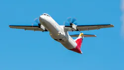 A white airplane with red and yellow accents on its tail flying in front of a blue sky A white airplane with red and yellow accents on its tail flying in front of a blue sky