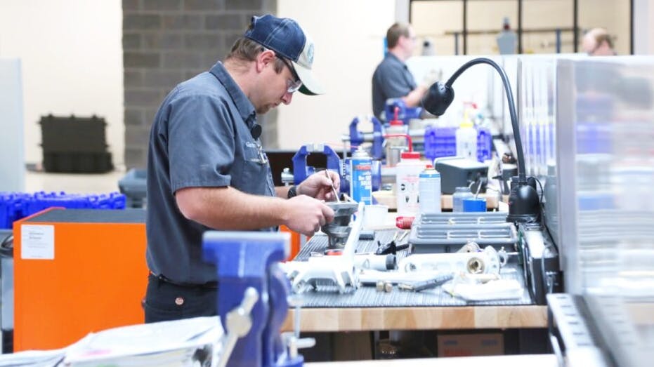 A technician at a work table repairing machinery components