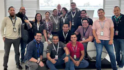 A large group of people wearing ID badges smiling at the camera A large group of people wearing ID badges smiling at the camera