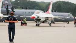 A man standing on a runway looking at an airplane parked on the ground, with aircraft in the background labeled 'U.S. Air Force' A man standing on a runway looking at an airplane parked on the ground, with aircraft in the background labeled 'U.S. Air Force'