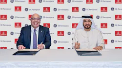Two men sitting at a table and smiling at the camera while signing documents in front of a backdrop displaying the logos for GE Aerospace and Emirates Two men sitting at a table and smiling at the camera while signing documents in front of a backdrop displaying the logos for GE Aerospace and Emirates