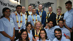 A group of technicians in light blue polo shirts posing with professionals in business attire A group of technicians in light blue polo shirts posing with professionals in business attire