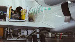 A technician on a lifted platform working next to a parked airplane inside a hangar A technician on a lifted platform working next to a parked airplane inside a hangar