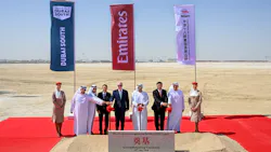A group of professionals wearing business attire posing with shovels at a construction site for a groundbreaking ceremony, with flags for Emirates, Dubai South and China Railway Construction Corporation in the background A group of professionals wearing business attire posing with shovels at a construction site for a groundbreaking ceremony, with flags for Emirates, Dubai South and China Railway Construction Corporation in the background
